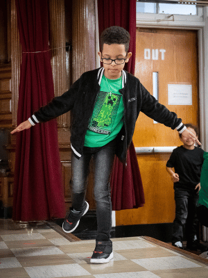 Boy balancing on one leg with arms out to the side